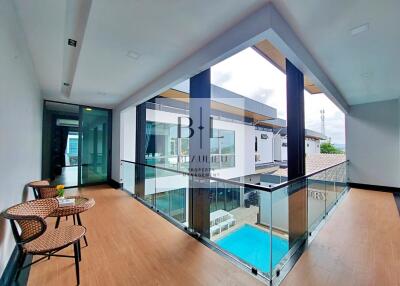 Modern corridor with glass railing and hardwood floors overlooking a pool