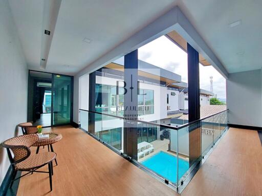 Modern corridor with glass railing and hardwood floors overlooking a pool