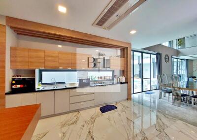 Modern kitchen with wooden and white cabinets, marble flooring, and dining area