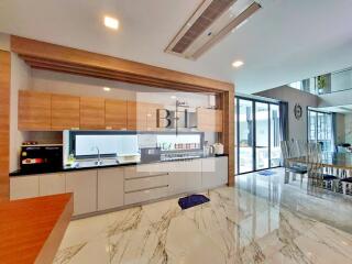 Modern kitchen with wooden and white cabinets, marble flooring, and dining area