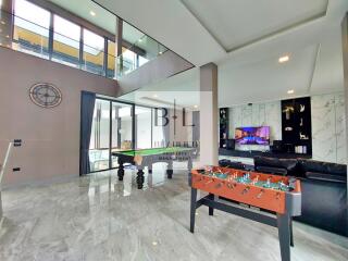 Spacious living area with large windows, pool table, and modern furnishings