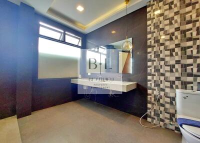 Modern bathroom with geometric tile accent wall and large mirror