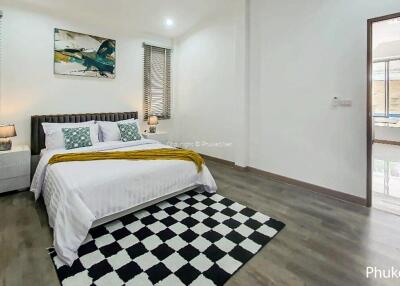 Modern bedroom with stylish decor, featuring a comfortable bed, checkered rug, and access to pool area