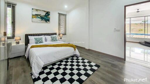 Modern bedroom with stylish decor, featuring a comfortable bed, checkered rug, and access to pool area