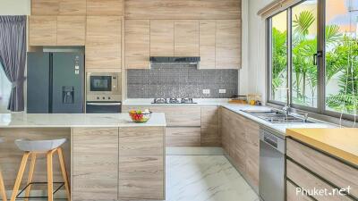 Modern kitchen with wooden cabinetry, island with seating, and large window