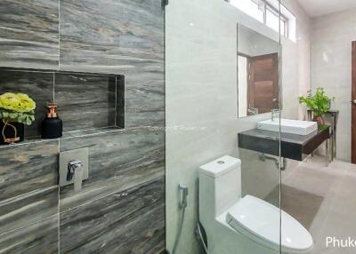 Modern bathroom with glass shower enclosure, toilet, and vanity with sink