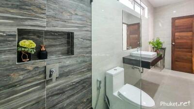 Modern bathroom with glass shower enclosure, toilet, and vanity with sink