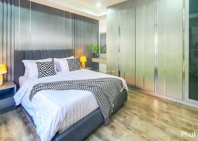 Modern bedroom with a large bed, bedside tables, lamps, and spacious wardrobe
