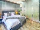 Modern bedroom with a large bed, bedside tables, lamps, and spacious wardrobe