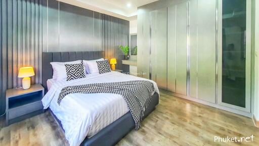 Modern bedroom with a large bed, bedside tables, lamps, and spacious wardrobe