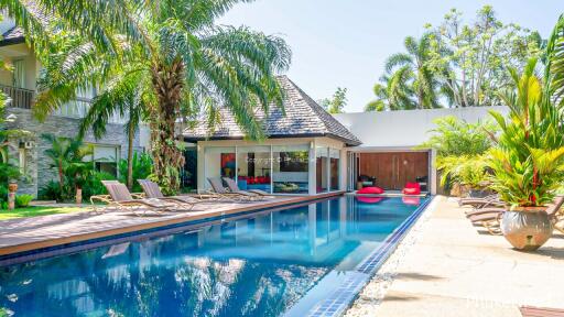 Luxurious swimming pool area in sunny weather with lounge chairs and palm trees