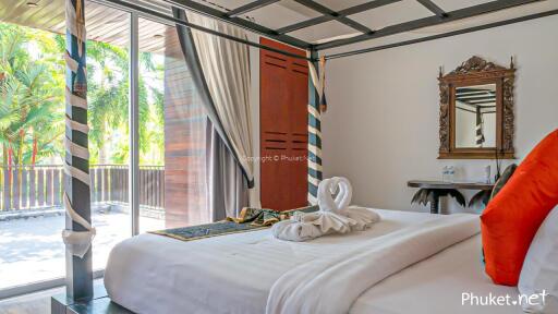 Bright bedroom with large glass doors leading to a balcony, featuring a neatly made bed