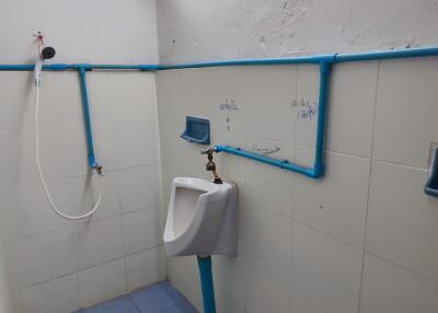 Bathroom with urinal and exposed piping