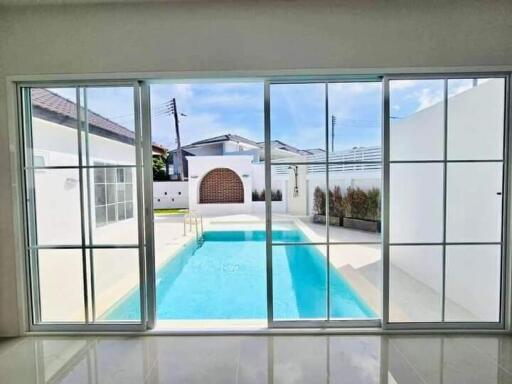 View of a swimming pool through large sliding glass doors