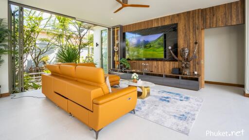 Modern living room with large TV, orange sofa, and garden view