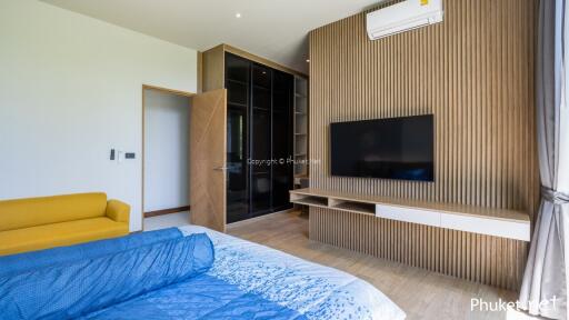 Modern bedroom with wooden paneling, wall-mounted TV, and stylish furnishings