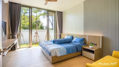 Bright modern bedroom with large windows, bed, and seating area