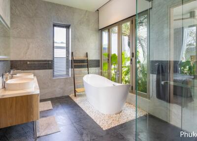 Spacious modern bathroom with freestanding bathtub, double sinks, and large windows