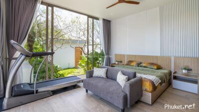 Modern bedroom with large windows, a treadmill, and sitting area