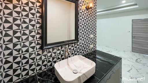 Modern bathroom with geometric tile wall and marble countertop