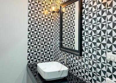 Stylish bathroom with geometric tiled walls, framed mirror and modern sink