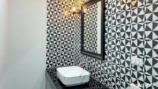 Stylish bathroom with geometric tiled walls, framed mirror and modern sink