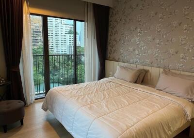 Bedroom with large bed, floral wallpaper, and balcony view