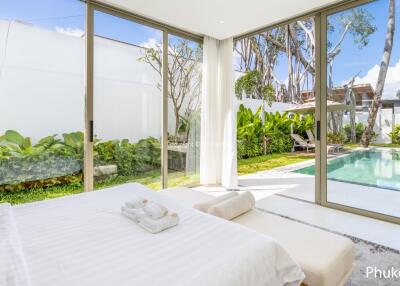 A bright and airy bedroom with a view of the pool and garden