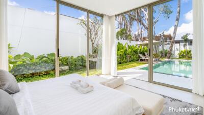 A bright and airy bedroom with a view of the pool and garden