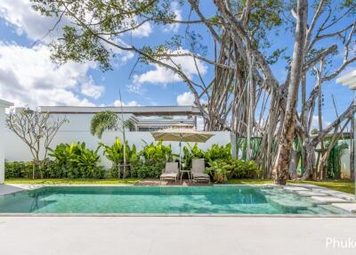 Swimming pool with lounge chairs and umbrella beside a garden