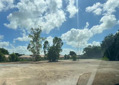 Vacant plot of land under a bright blue sky with scattered clouds