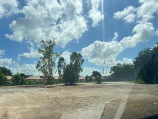 Vacant plot of land under a bright blue sky with scattered clouds