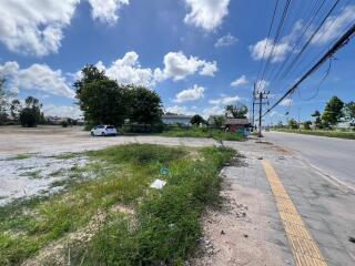 Vacant land on a sunny day with a car parked and adjacent to the main road