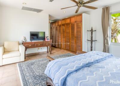 Spacious bedroom with large window, wooden closets, and ceiling fan