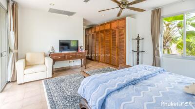 Spacious bedroom with large window, wooden closets, and ceiling fan