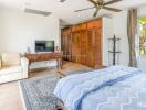 Spacious bedroom with large window, wooden closets, and ceiling fan