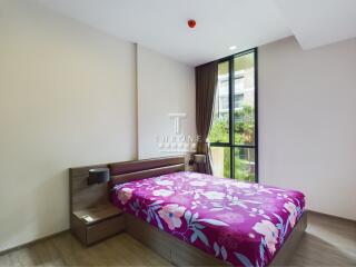 Modern bedroom with large window and colorful bedspread