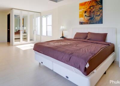 Spacious bedroom with bed, bedside tables, lamps, and large mirrored wardrobe