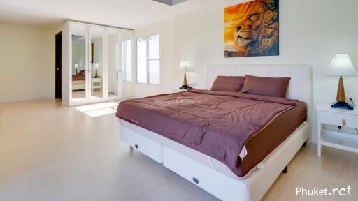 Spacious bedroom with bed, bedside tables, lamps, and large mirrored wardrobe