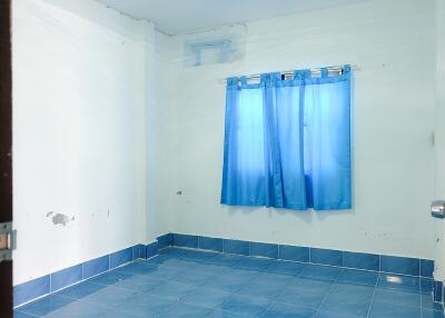 Empty bedroom with blue curtains and tiled floor