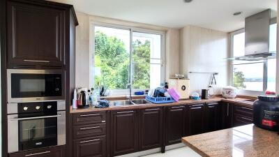 Modern kitchen with dark wood cabinets and a view of greenery