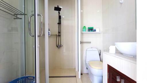 Modern bathroom with a glass shower door, toilet, sink, and storage shelves