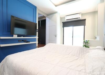 Bedroom with blue accent wall, TV, and white bedding