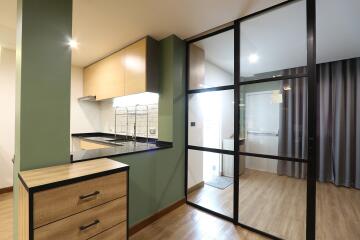 Modern kitchen with green wall, wooden drawers, and a glass door