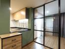 Modern kitchen with green wall, wooden drawers, and a glass door