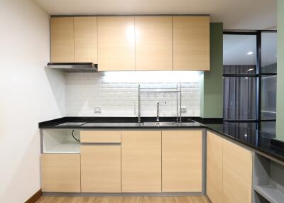 Modern kitchen with light wood cabinets and black countertops