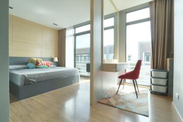 Modern bright bedroom with large windows, bed, and study area