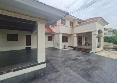 Front view of a large residential building with a spacious driveway and covered parking area