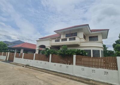 Exterior view of a two-story house with a red roof and wooden fence