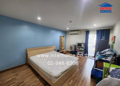 Spacious bedroom with wooden flooring and blue accent wall